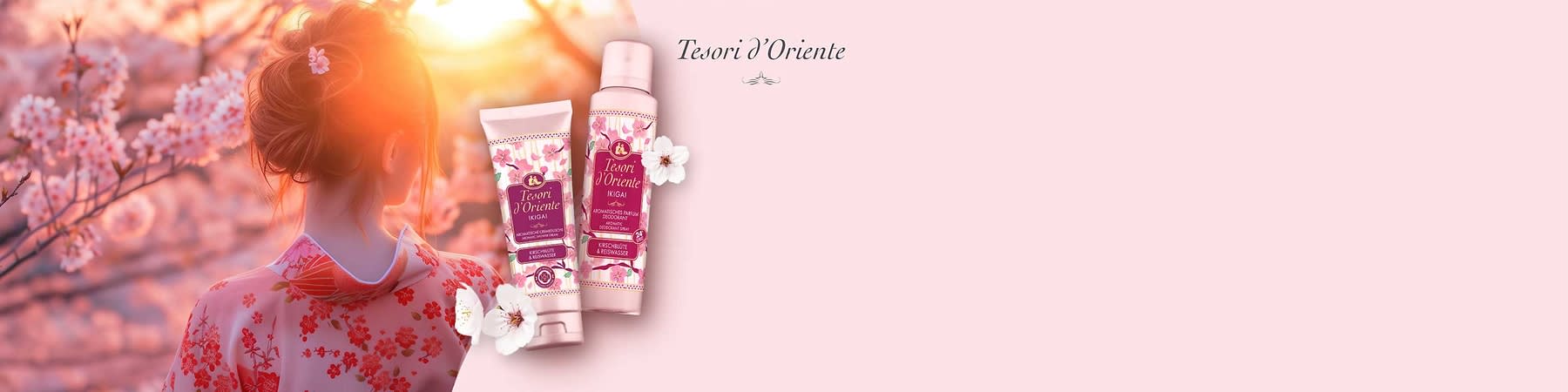Zwei rosafarbene Produktverpackungen der Marke „Tesori d’Oriente“ mit Aufschrift „Yokai“ und floraler Gestaltung, eine Tube und eine Sprühflasche, dekorativ mit weißen Blüten auf hellem rosa Hintergrund