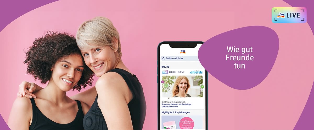 Zwei Frauen stehen nebeneinander vor einem rosa Hintergrund, die linke Frau hat lockiges dunkles Haar und trägt ein schwarzes ärmelloses Oberteil, die rechte Frau hat kurzes blondes Haar und trägt ebenfalls ein schwarzes ärmelloses Oberteil, beide haben ihre Gesichter verschwommen, oben rechts steht in einem lila Bereich der Text Wie gut Freunde tun und daneben ist das dm LIVE Logo mit einem kleinen Regenbogenrahmen sichtbar