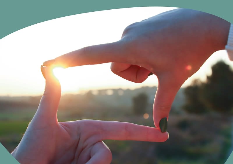 Foto von zwei Händen die ienen Blick in den Hintergrund bieten