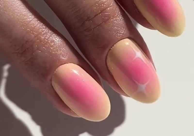 Hand mit rosa-gelben Ombre-Nägeln