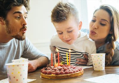 Feste feiern trotz Corona: Kind pustet gemeinsam mit Mama und Papa Geburtstagskerzen aus
