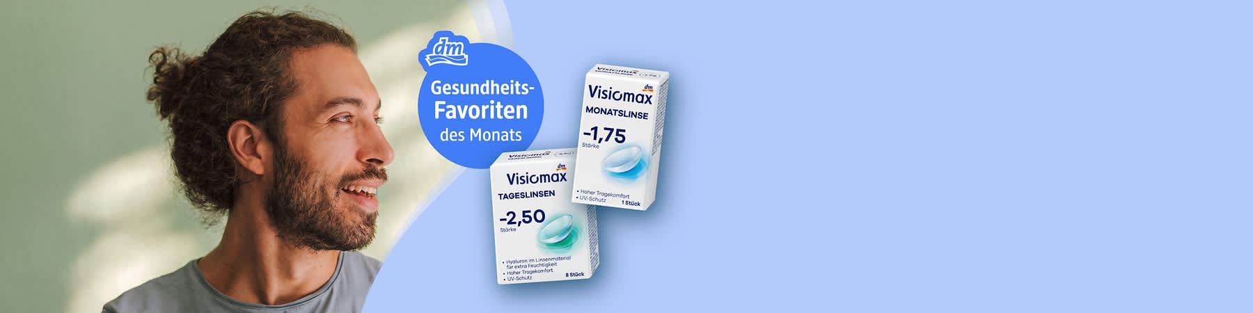 Porträt eines lächelnden Mannes links und rechts zwei Produktverpackungen von dm-Visiomax-Kontaktlinsen mit sichtbaren Texten „Visiomax TAGESLINSEN -2,50“ und „Visiomax MONATSLINSE -1,75“ sowie blauem Badge „Gesundheits-Favoriten des Monats“. Bild mithilfe von KI erstellt