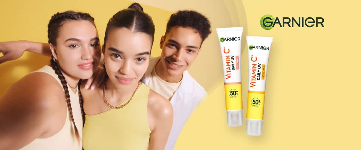 Zwei Tuben mit der Aufschrift „Vitamin C Daily UV“ und „SPF 50+“ von Garnier, eine mit „Bright“ und die andere mit „Matte“ gekennzeichnet, auf gelbem Hintergrund. Oben rechts das Logo von Garnier