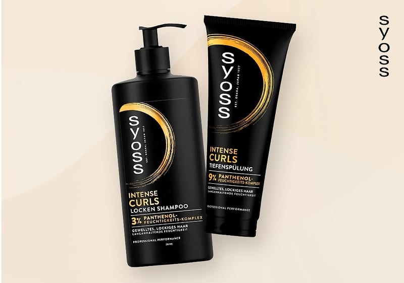 Zwei schwarze Produktverpackungen der Marke Syoss auf einem beigen Hintergrund, links eine Flasche mit Pumpspender und der Aufschrift "Syoss Intense Curls Locken Shampoo", rechts eine Tube mit der Aufschrift "Syoss Intense Repair Tiefenspülung" und das Syoss-Logo ist vertikal am rechten Rand des Bildes zu sehen