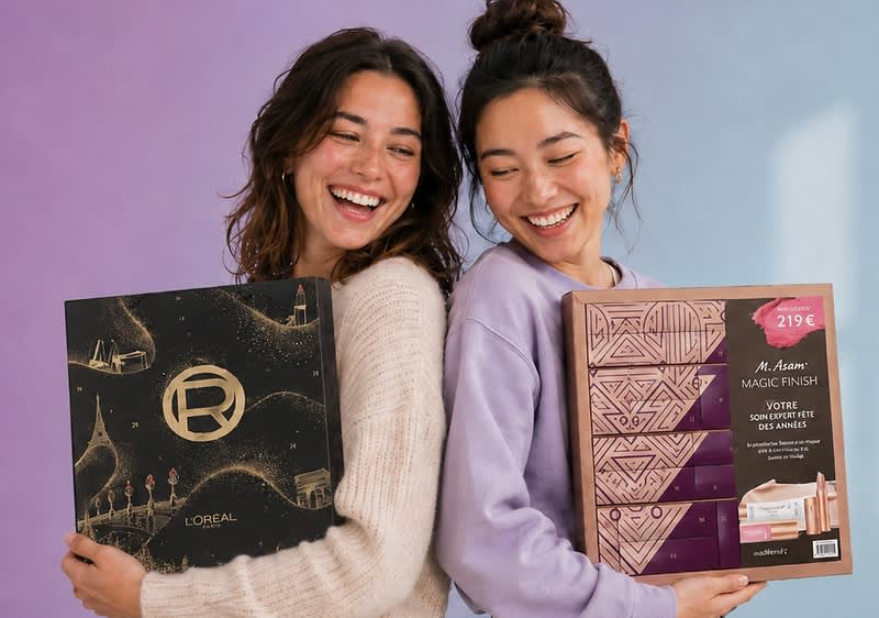 Zwei lächelnde Frauen stehen Rücken an Rücken und halten je eine Geschenkbox: links eine schwarze L’Oréal-Box mit goldenen Ornamenten und Markenlogo, rechts eine beige-violette Box von M. Asam mit sichtbarem Preisaufkleber „219 €“ und der Aufschrift „Magic Finish“
