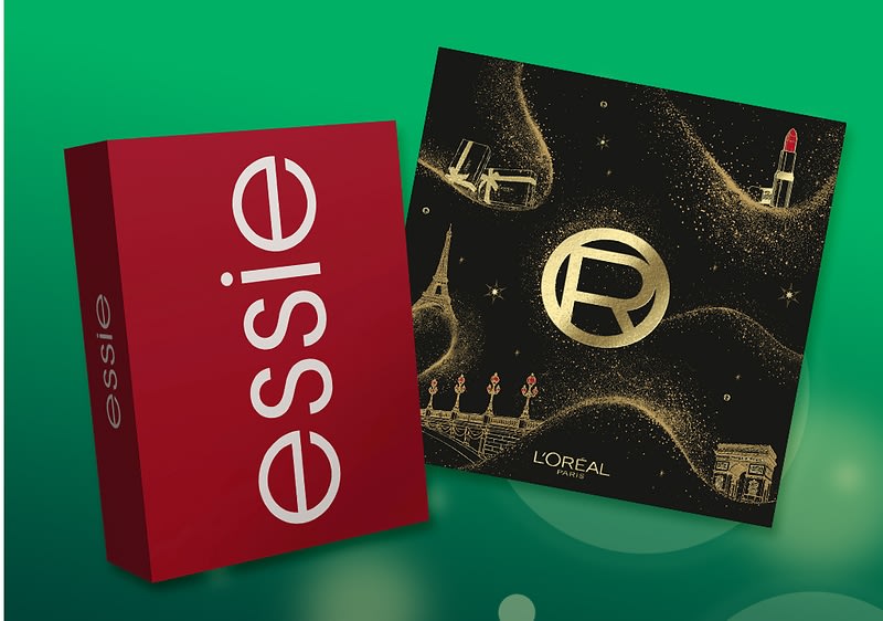 Rote Geschenkbox im Hochformat mit weißem Schriftzug „essie“ neben schwarzer quadratischer Geschenkverpackung mit goldenen Ornamenten, goldem Kreislogo „R“ und kleinem Schriftzug „L’ORÉAL PARIS“. Bild mithilfe von KI erstellt