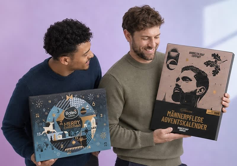 Zwei Männer halten Adventskalender; links ein blauer Balea Men Adventskalender mit Winterlandschaft und der Aufschrift „Merry Christmas“, rechts ein brauner „Männerpflege Adventskalender“ mit stilisiertem Männerporträt und Text „Brooklyn Soap Company“. Bild mithilfe von KI erstellt
