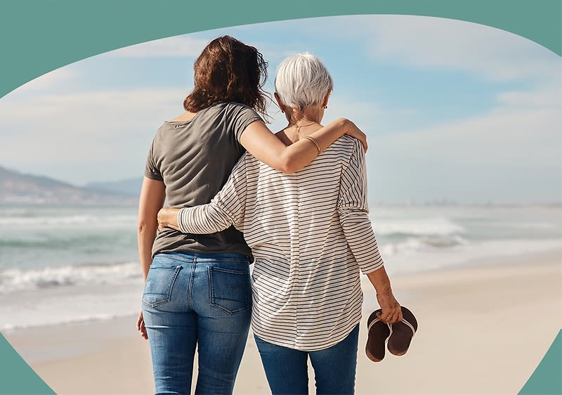 Frau und ältere Frau umarmen sich am Strand