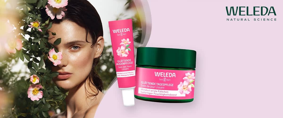 Zwei Weleda-Produkte mit pinker Verpackung und floralen Motiven, links eine Tube mit der Aufschrift Glättende Augenpflege und rechts ein Tiegel mit der Aufschrift Glättende Tagespflege, beide Produkte versprechen die Minderung erster Fältchen und einen sofortigen Feuchtigkeitsboost, im Hintergrund das Weleda-Logo mit dem Schriftzug Natural Science