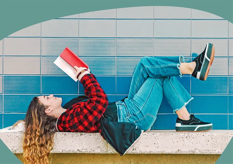 Frau liest Buch auf Bank