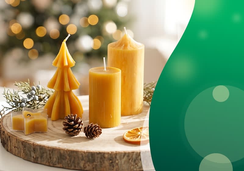 Drei gelbe Bienenwachskerzen in verschiedenen Formen (zylindrisch, kegelförmig, Tannenbaum), liegend auf einer Holzscheibe neben zwei Kiefernzapfen, getrockneten Orangenscheiben und kleinen Deko-Teelichthaltern vor unscharfem Weihnachtsbaumlicht. Bild mithilfe von KI erstellt