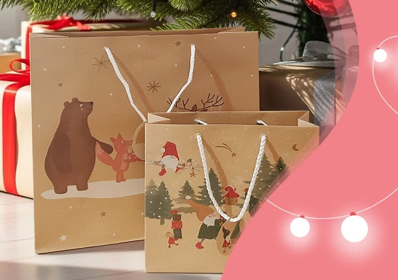 Zwei braune Geschenktüten mit weißen Kordeln, die größere zeigt einen Bären und einen Fuchs, die kleinere zeigt Weihnachtsmänner und Tannenbäume