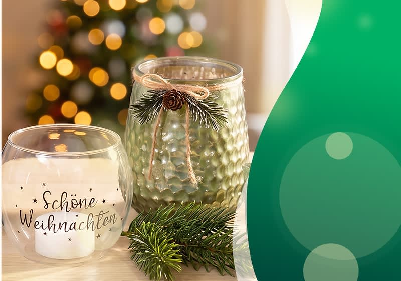 zwei dekorative Kerzengläser auf Holz: links rundes Glas mit brennender Kerze und Aufschrift „Schöne Weihnachten“, rechts grünlich strukturiertes Glas mit Zierschnur, einer kleinen Tannenzapfen-Dekoration und Tannenzweigen, rechter Bildrand mit grünem grafischem Bogen. Bild mithilfe von KI erstellt