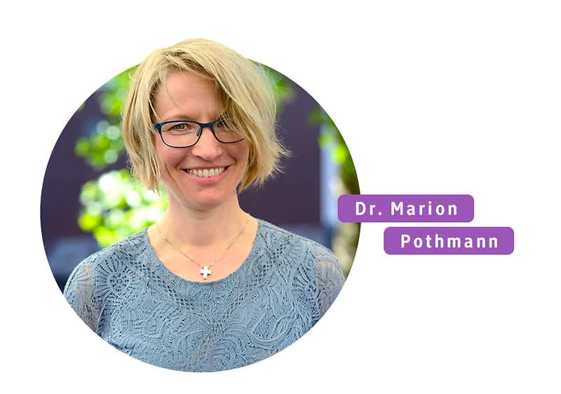 Person mit blonder Kurzhaarfrisur und blauem Oberteil