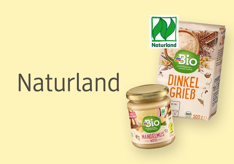 Zwei Produktverpackungen von dmBio, oben eine Packung Dinkelgrieß mit der Aufschrift „Dinkelgrieß“ und unten ein Glas Mandelmus mit der Aufschrift „Mandelmus weiß“, daneben das Naturland-Logo und der Text „Naturland“