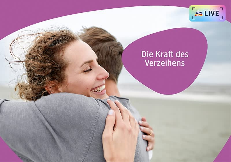 Zwei Personen umarmen sich innig am Strand, wobei die Gesichter der Personen verschwommen sind, im Hintergrund ist der Himmel bewölkt und auf der rechten Seite des Bildes steht in einem lila Feld der Text Die Kraft des Verzeihens.