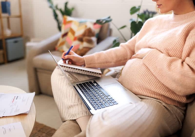Schwangere Frau arbeitet am Laptop