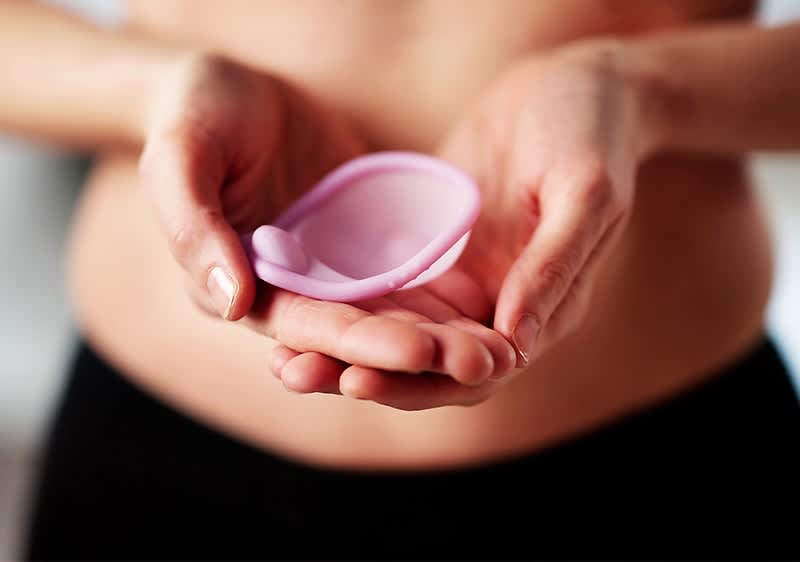 Eine Person hält ein rosafarbenes Diaphragma in beiden Händen vor ihrem Bauch