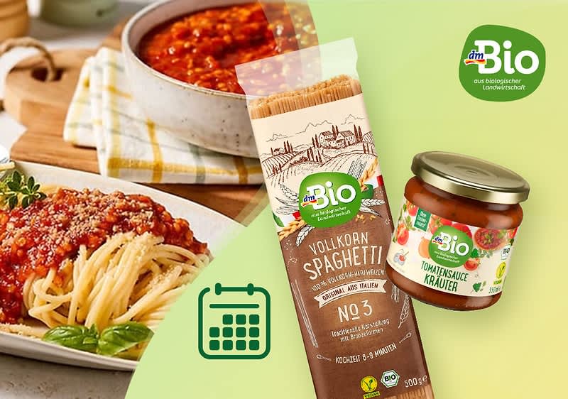 Eine Packung dmBio Vollkorn-Spaghetti neben einem Glas dmBio Tomatensauce Kräuter, im Hintergrund ein Teller mit Spaghetti und Tomatensauce