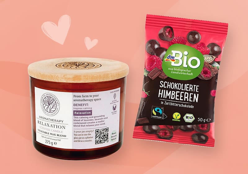 Eine braune Aromatherapie-Kerze mit Holzdeckel und weißem Etikett neben einer Verpackung von dmBio Schokolierte Himbeeren in Zartbitterschokolade mit Himbeeren und Schokoladenstücken darauf