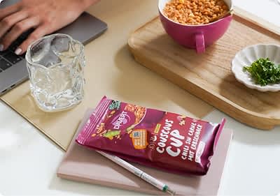 Eine Tasse voller Couscous steht auf einem Schreibtisch.