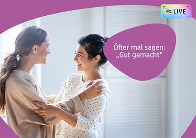 Zwei Frauen stehen sich gegenüber und umarmen sich sanft, beide haben ein verschwommenes Gesicht, die Frau links trägt ein beiges Oberteil, die Frau rechts ein weißes Oberteil mit Punkten, im Hintergrund sind helle Wände und ein Fenster zu sehen.