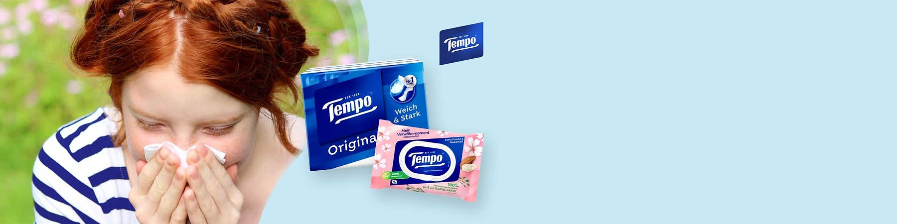 Zwei Tempo-Taschentuchprodukte: links eine blaue Packung „Tempo Original“ mit Aufschrift „Weich & Stark“, rechts vorne eine rosa Feuchttuch-Packung „Tempo“ mit Blumenmotiv und Zusatztext „Mein Verwöhnmoment“