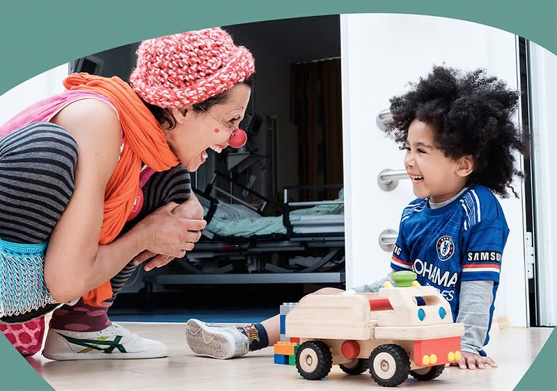 Erwachsene Person spielt mit Kind und Holzauto