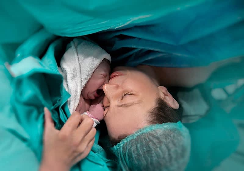 Neugeborenes wird von Eltern gehalten