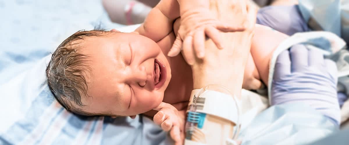 Neugeborenes Baby weint im Krankenhausbett