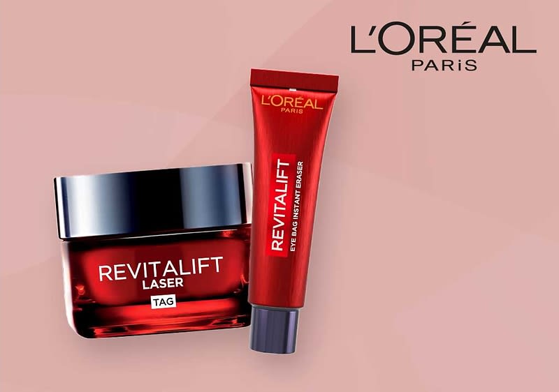 Zwei L'Oréal Paris Revitalift Produkte auf einem rosa Hintergrund, links eine rote Tube mit der Aufschrift Revitalift Eye Bag Instant Eraser und rechts ein quadratisches Glasgefäß mit schwarzem Deckel und der Aufschrift Revitalift Laser X3 Tag, oben rechts das L'Oréal Paris Logo