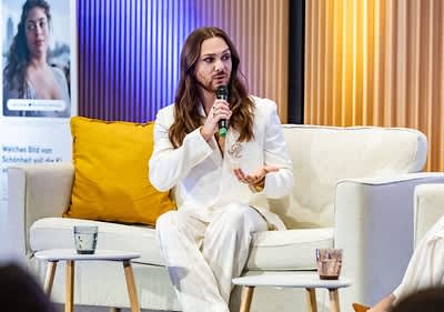 Ricardo Simonetti in weiĂem Anzug spricht auf Sofa