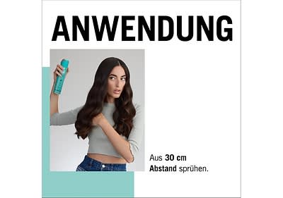 Frau sprüht Haarspray auf ihr Haar