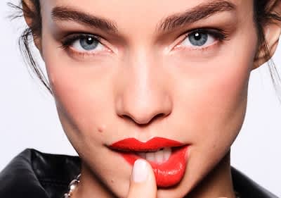 Frau fährt mit Finger über ihre geschminkten Lippen