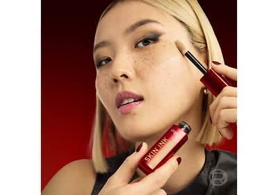 Frau trägt Concealer auf die Haut auf