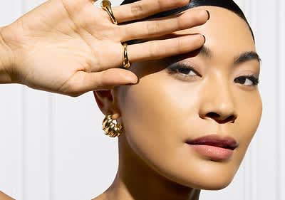 Frau schützt sich mit Hand vor Sonne.