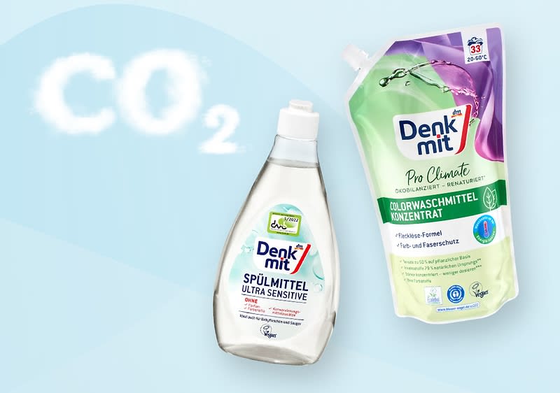 Zwei Produktverpackungen der Marke Denkmit, links eine transparente Flasche mit der Aufschrift „Spülmittel Ultra Sensitive“, rechts ein grüner Beutel mit der Aufschrift „Pro Climate Colorwaschmittel Konzentrat“ und CO₂-Symbol in weißer Schrift oben links