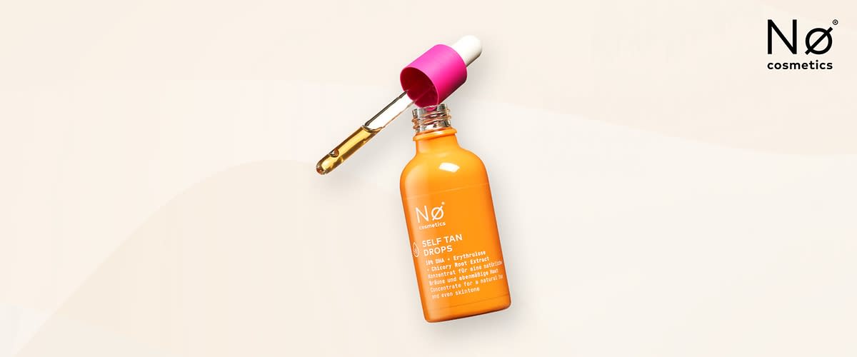 Eine orangefarbene Flasche mit der Aufschrift Nø cosmetics SELF TAN DROPS und weiteren Angaben wie 10% DHA + Beet Extract und Glowy & Deep Tan Effect liegt auf einem hellen Hintergrund, daneben ein pinker Pipettendeckel mit einer transparenten Pipette, die eine gelbliche Flüssigkeit enthält, oben rechts steht Nø cosmetics in schwarzer Schrift.