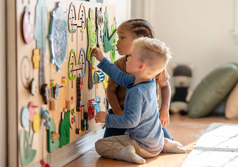Kinder spielen an Wandspielzeug
