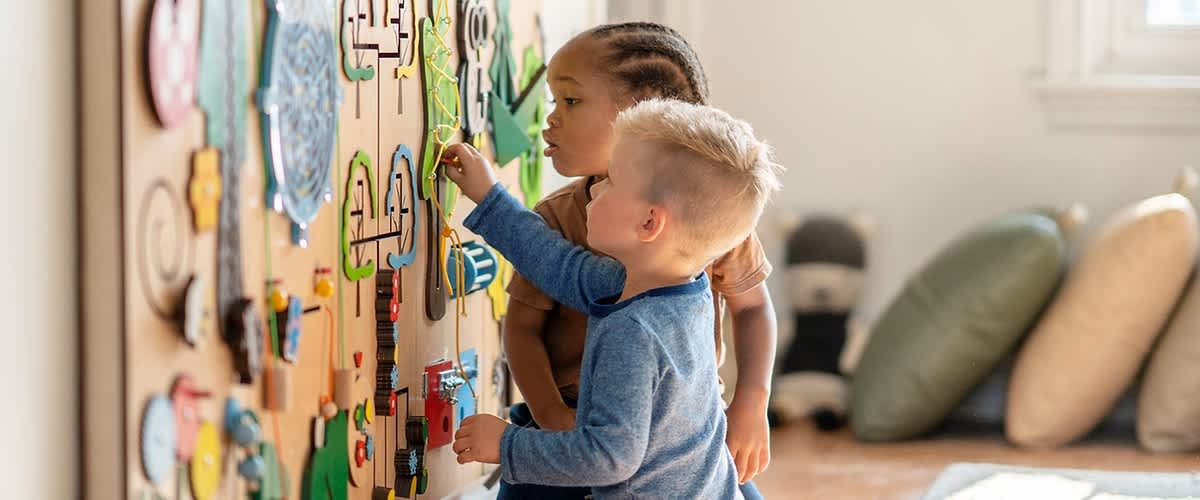 Kinder spielen an Wandspielzeug