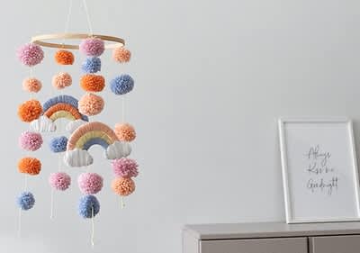 Bunte Pompons und Regenbogen-Mobile hängen