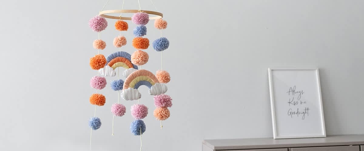 Bunte Pompons und Regenbogen-Mobile hängen