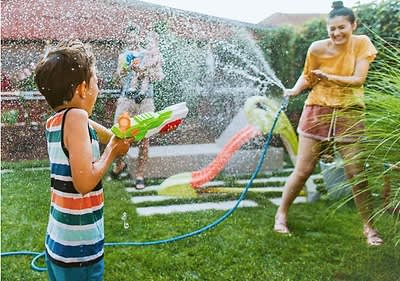 Kinder spielen mit Wasserpistolen im Garten