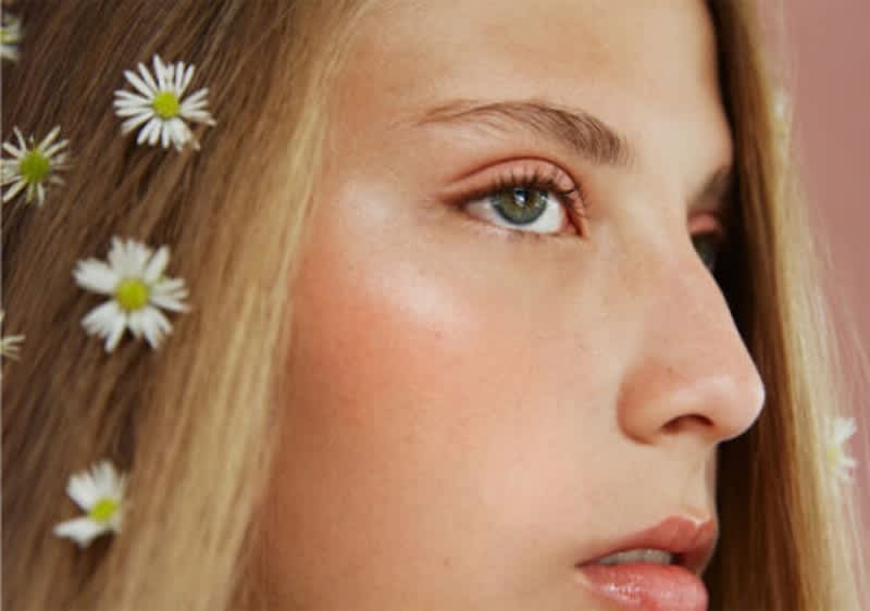 Frau mit grünen Augen und Blüten in ihrem blonden Haar