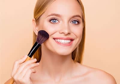 Frau hält Make-up-Pinsel am Gesicht