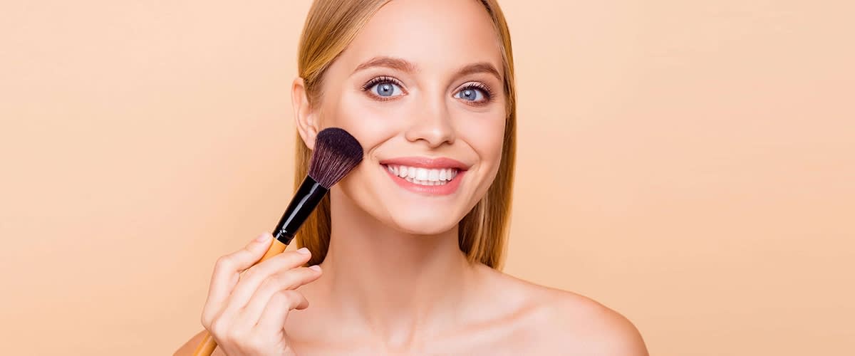 Frau hält Make-up-Pinsel am Gesicht