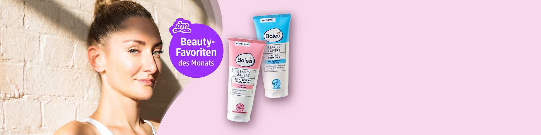 dm-Logo und lila Kreis mit Text „Beauty-Favoriten des Monats“, rechts zwei Balea Tuben „Beauty Expert“ (rosa Tube „Skin Refining Body Wash“, blaue Tube „Hydro Body Wash“), links unscharfe Person in weißem Top, Pastellrosa Hintergrund