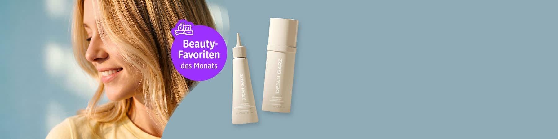 Seitliches Porträt einer lächelnden Frau mit blonden Haaren links, rechts zwei beige kosmetische Produktverpackungen mit Aufschrift „DEJAN GARZ“, mittig violetter Kreis mit dm-Logo und Text „Beauty-Favoriten des Monats“. Bild mithilfe von KI erstellt