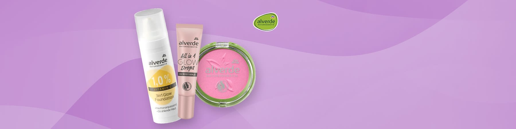 Eine rosa Tube mit der Aufschrift „alverde NATURKOSMETIK All in 1 GLOW Drops 02 ROSY GOLD“ und ein runder, rosa Puder mit der Aufschrift „alverde NATURKOSMETIK“ auf einem lila Hintergrund, oben rechts das Logo von alverde NATURKOSMETIK