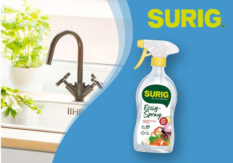 Eine Illustration zeigt eine Küche mit einem modernen Wasserhahn und grünen Pflanzen auf der linken Seite, daneben eine Flasche SURIG Essig-Spray mit grünem Etikett, auf dem Essig-Spray und Ideal für Küche und Bad steht, sowie Bilder von Tomaten, Zwiebeln und Kräutern, oben rechts steht der Markenname SURIG in gelber Schrift auf blauem Hintergrund.